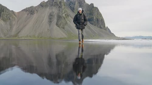 Hiker Walking Along Black Sand Beach Towards Camera