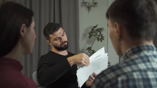 Psicólogo masculino caucásico guapo con cabello negro mostrando a los pacientes manchas de tinta Rorschach