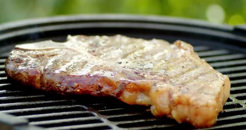 Steak T-Bone wird mit Rauch gegrillt.