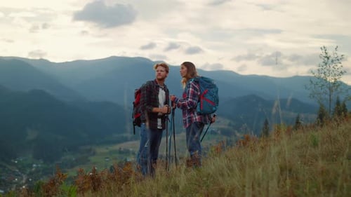 Couple Hiking with Backpacks on Mountain Hilltop