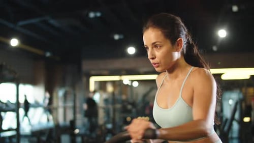 Cute Fitness Woman Training at Gym. Fit Girl Using Velosimulator in Sport Club