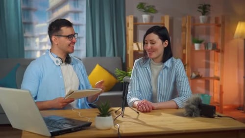 Man and a Woman Sitting in a Home Recording Studio Recording a Podcast Interview