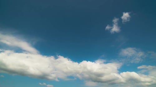 Mouvement intense de nuages blancs et gris au-dessus du ciel bleu.