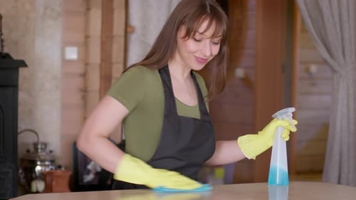 Young Woman Cleaning a Table with Spray Bottle