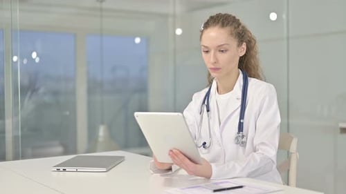 Hardworking Young Female Doctor Using Tablet in Office