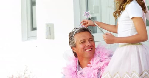 Daughter in angel costume putting crown on father head 4k