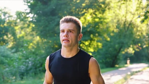 Slow Motion Man Breathing Hard While Running in Park