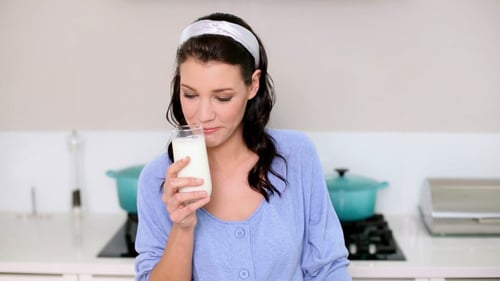 Woman Drinks Glass of Milk in Kitchen
