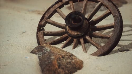Weathered Wooden Wagon Wheel Partially Buried in Sand