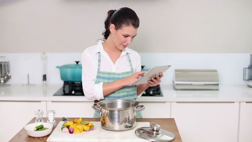 Woman Prepares Food Using Tablet in Bright Kitchen