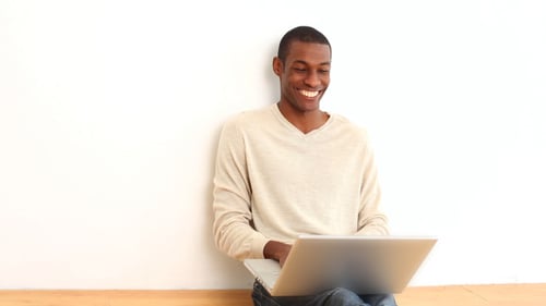 Smiling Man Using Laptop While Sitting on Floor