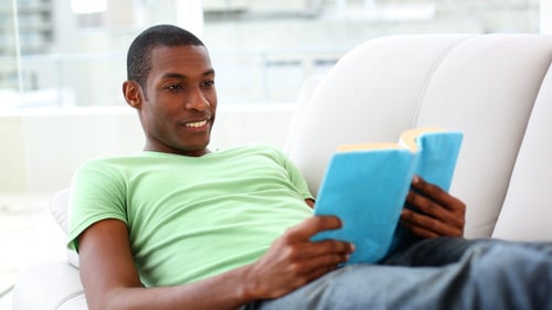 Adult Smiling Reading on White Couch Indoors