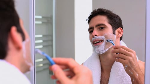 Homem bonito olhando para o espelho e fazendo a barba