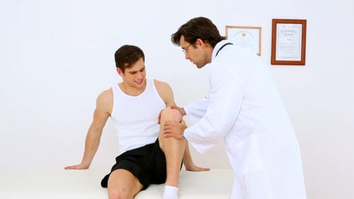 Doctor Examining Patient's Knee in Medical Office