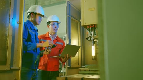 Male Asian engineer professional having a discussion standing consult cnc machine