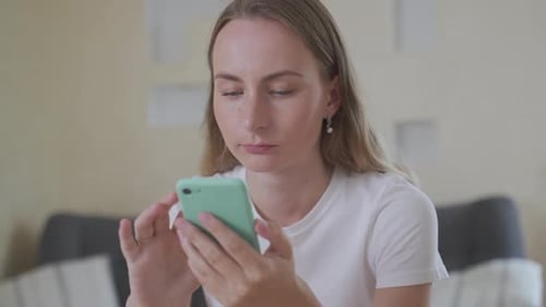 Smiling Woman Uses Smartphone at Home Indoors