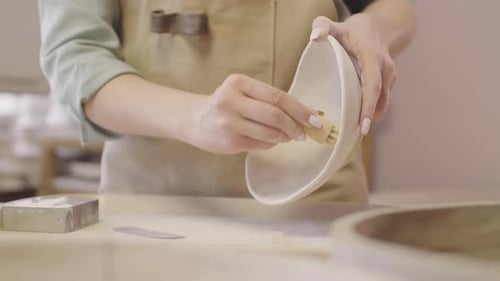 Woman sanding inside of ceramic bowl at workplace