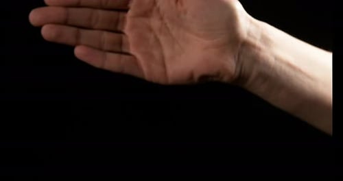 Hand Clenches Into Fist Against Black Background