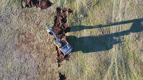 Excavator Digging Trench in Rural Field