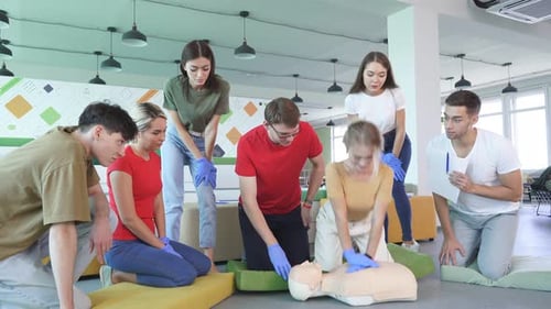 Young Female Learning How To Make First Aid Heart Compressions with Dummies During the Training