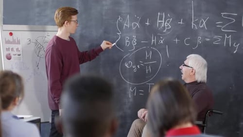 Student and Teacher Discussing Equation at Blackboard
