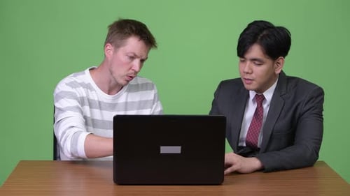 Two Men Discuss Business Using Laptop