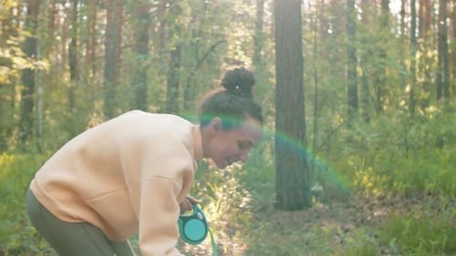 Woman Training Dog in a Sunny Forest