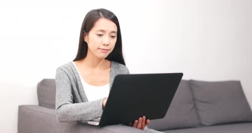 Woman Using Laptop Computer at Home on Sofa