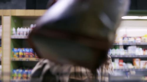 Woman Examining Package in Supermarket Aisle
