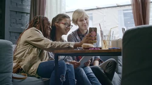 Teenage Girls Photographing with Smartphone in Cafe