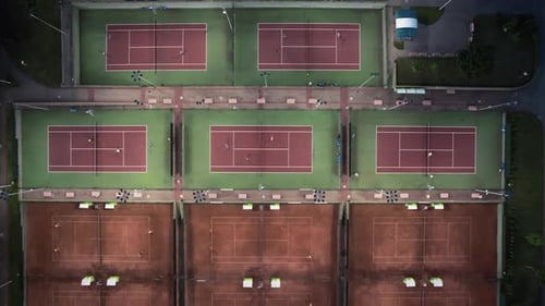 Aerial top view of the sports club with lot of dirt tennis courts in the evening.