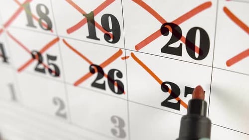 Female Hand Crosses with Red Marker the Calendar Day 27. Slow Motion Shot. Close Up