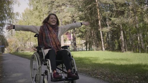 Woman Smiling and Wheeling in Wheelchair on Path