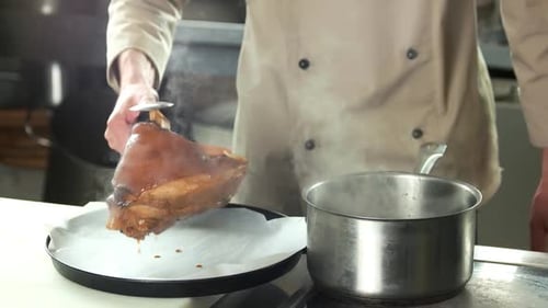 Chef Prepares Steaming Ham Hock in Kitchen