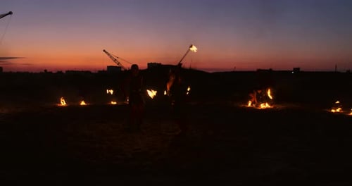 Professionelle Künstler zeigen eine Feuershow bei einem Sommerfestival im Sand in Zeitlupe