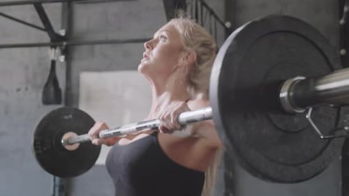 Strong Woman Lifting Barbells in Gym