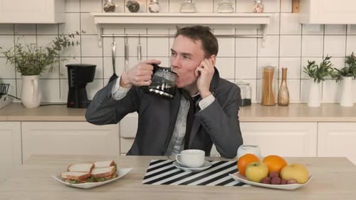 Sleepy Man Drinking Coffee from Pot in Kitchen