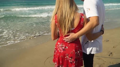 Young Couple Standing at the Beach Admiring Beautiful Seascape, Man and Woman Cuddling