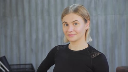 Portrait of a young athletic attractive woman smiling and posing in front of the camera in the gym.