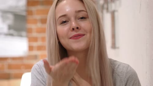 Friendly Woman Waving and Talking Indoors