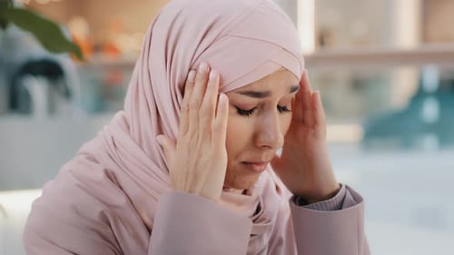 Woman with Headscarf Massaging Temples in Distress