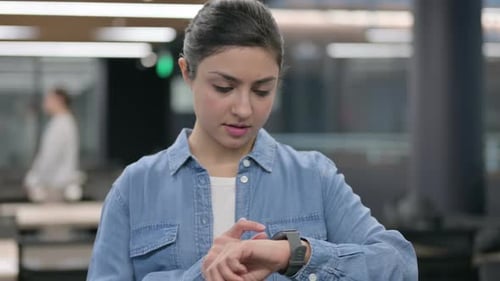 Woman Interacting With Smart Watch in Office