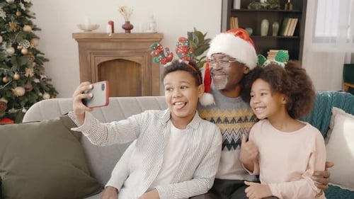 Smiling Family Taking Christmas Selfie on Sofa