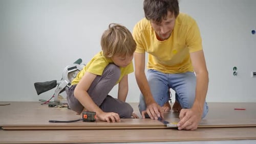 Child and Adult Installing Wood Flooring Together