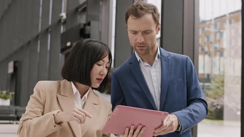 Business People Reviewing Tablet in Modern Lobby