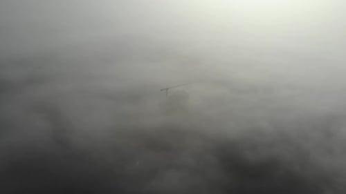 Birds eye view on tower crane in fog standing next to residential building.