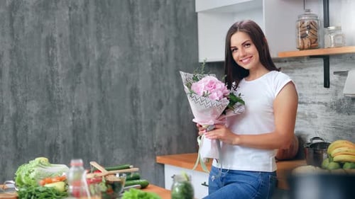 Smiling Woman Holds Bouquet in Kitchen Setting
