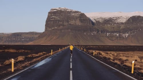 Man Running Along an Empty Asphalt Mountain Road in Iceland