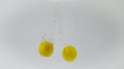 Lemons Dropping Into Clear Water