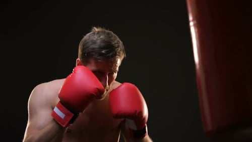 Muscular Man Punching Red Boxing Bag